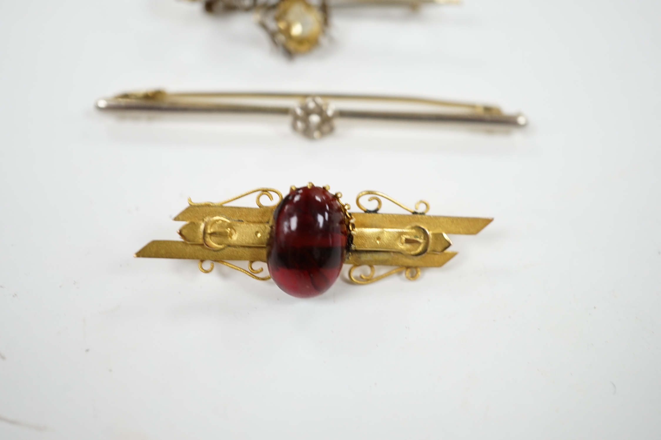 An Edwardian 15ct and diamond cluster set bar brooch, 60mm and two other gem set bar brooches including a bug brooch.